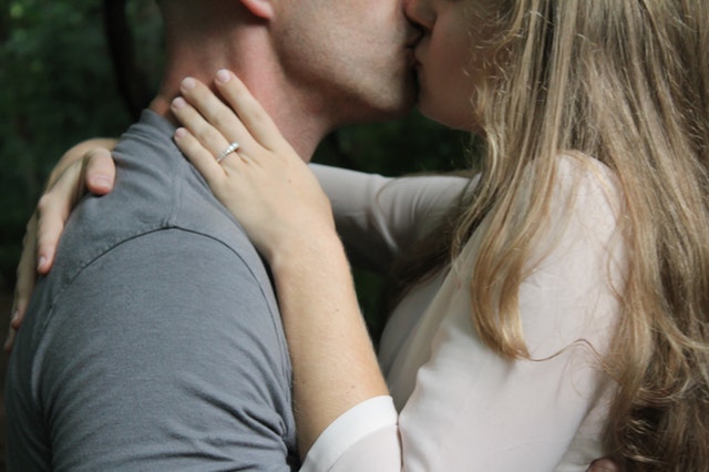 muž a žena polibek, ona má ruku na jeho krku, má prstýnek a světlou halenku